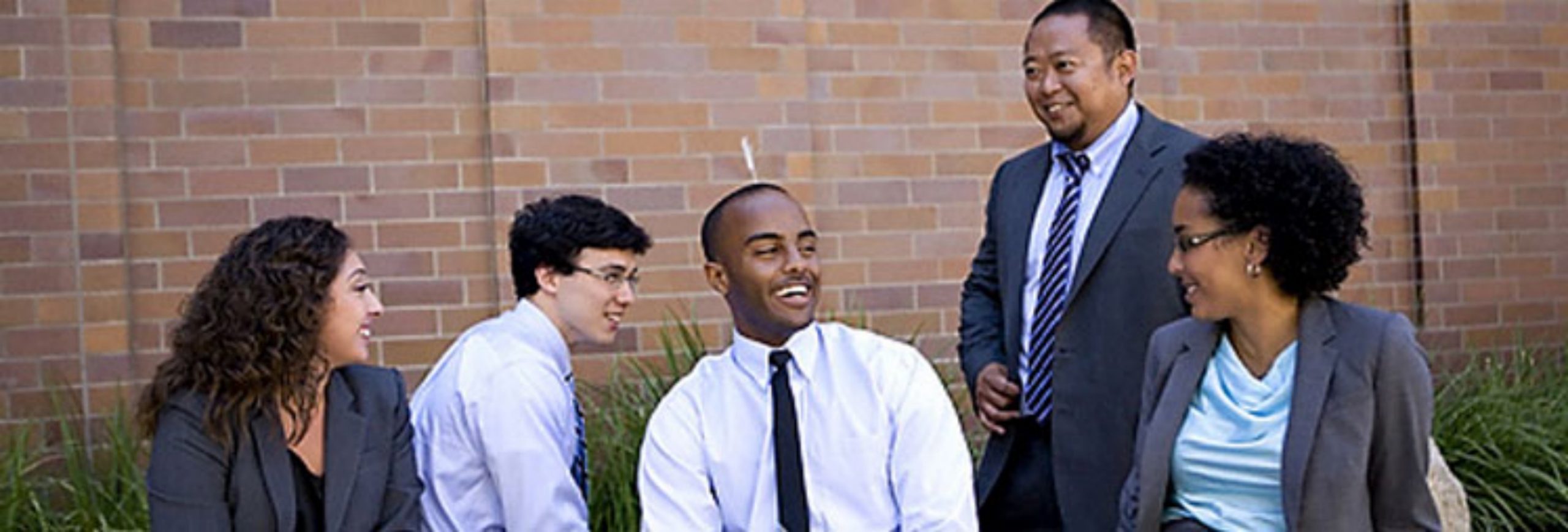 Five Competitive Edge participants smile in front of a brick wall